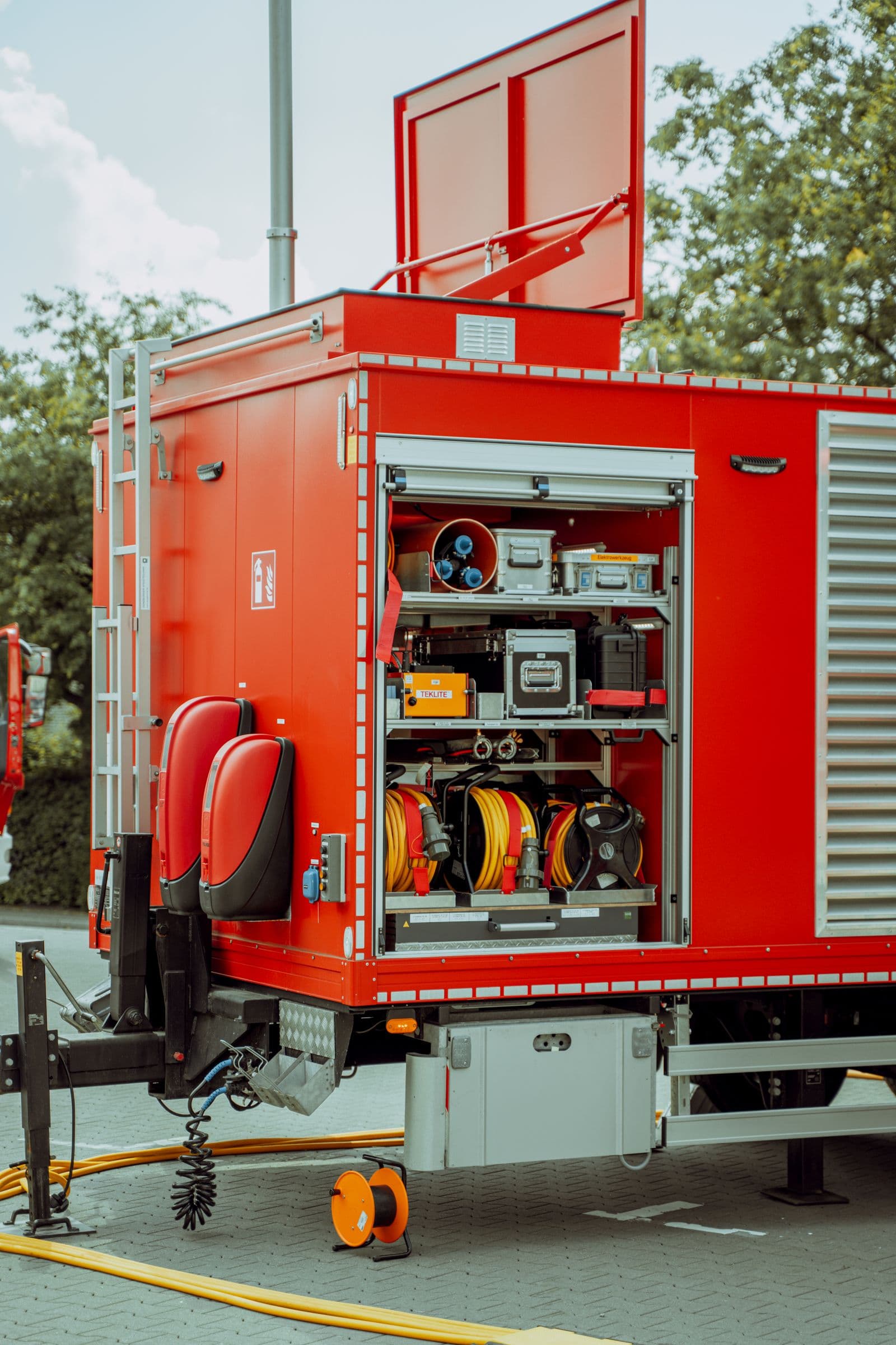 Open exterior equipment compartment on an emergency vehicle showing hose reels and storage