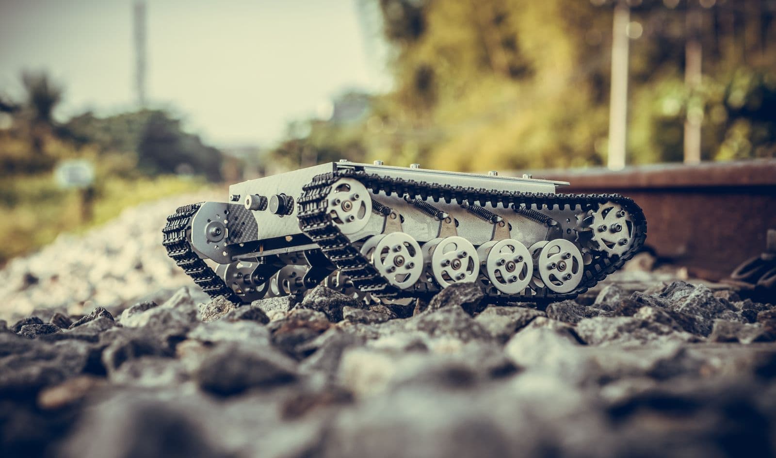 Tracked ground-vehicle chassis with visible metal frame and rollers on rough terrain